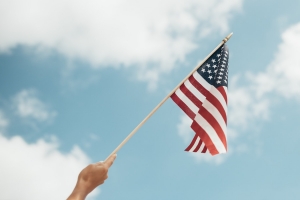 Photo of a hand waving a small American flag