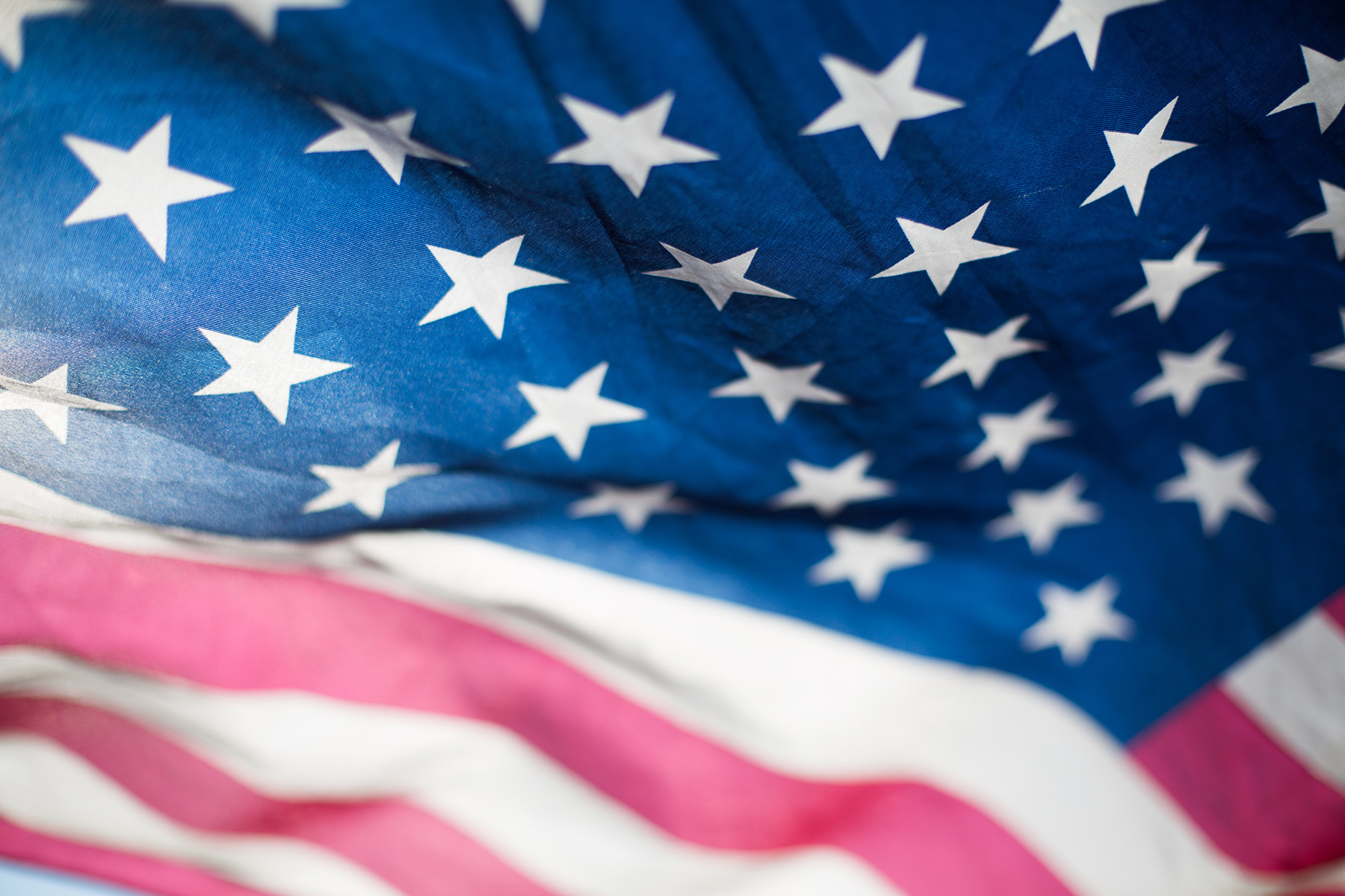 A majestic USA flag waving against a clear sky, symbolizing the nationwide impact of your car donation to the Troops Relief Fund.