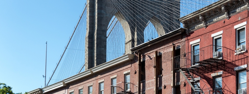 Brooklyn Bridge arching over historic brick facades in Brooklyn