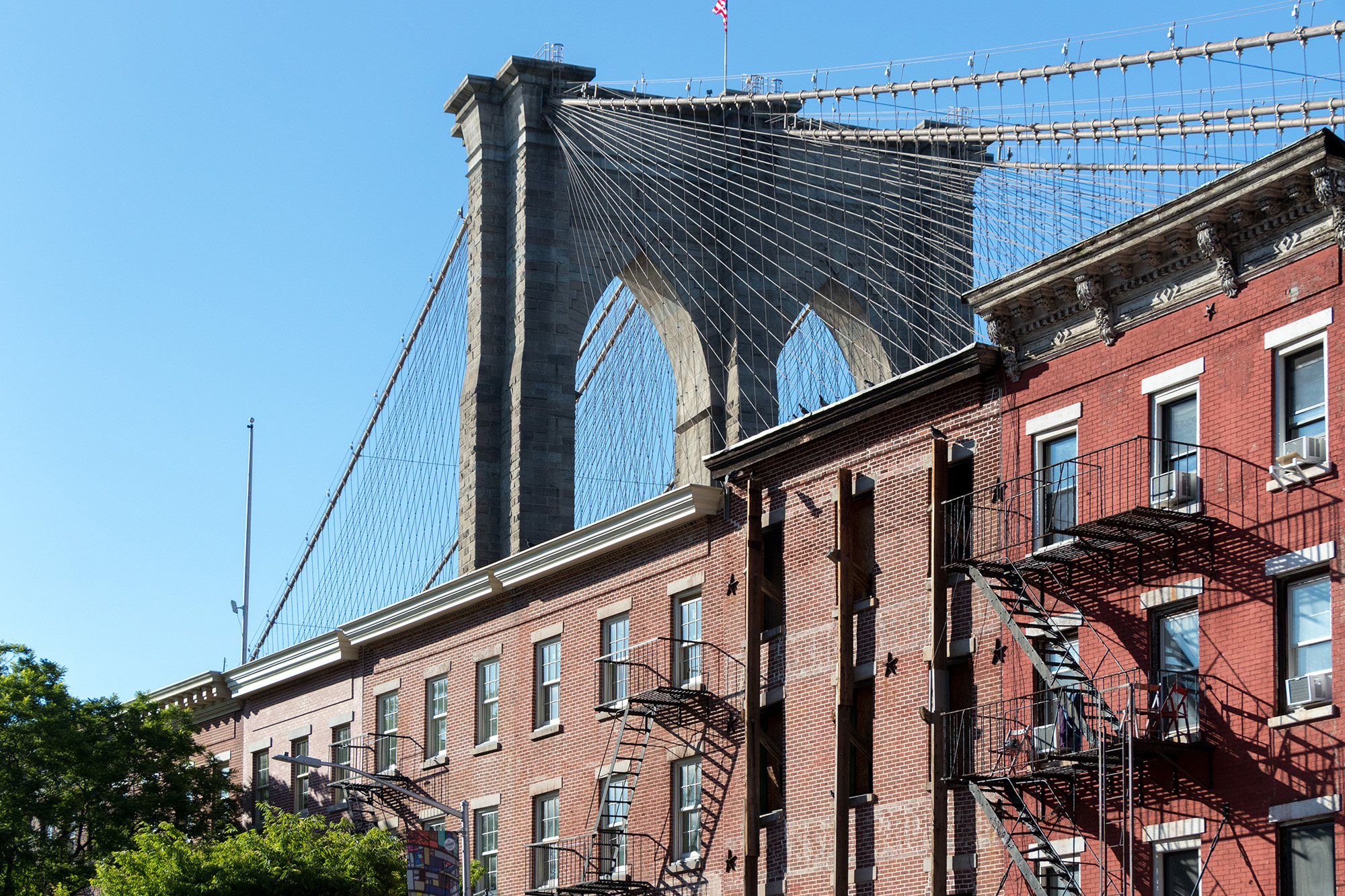 Brooklyn Bridge arching over historic brick facades in Brooklyn