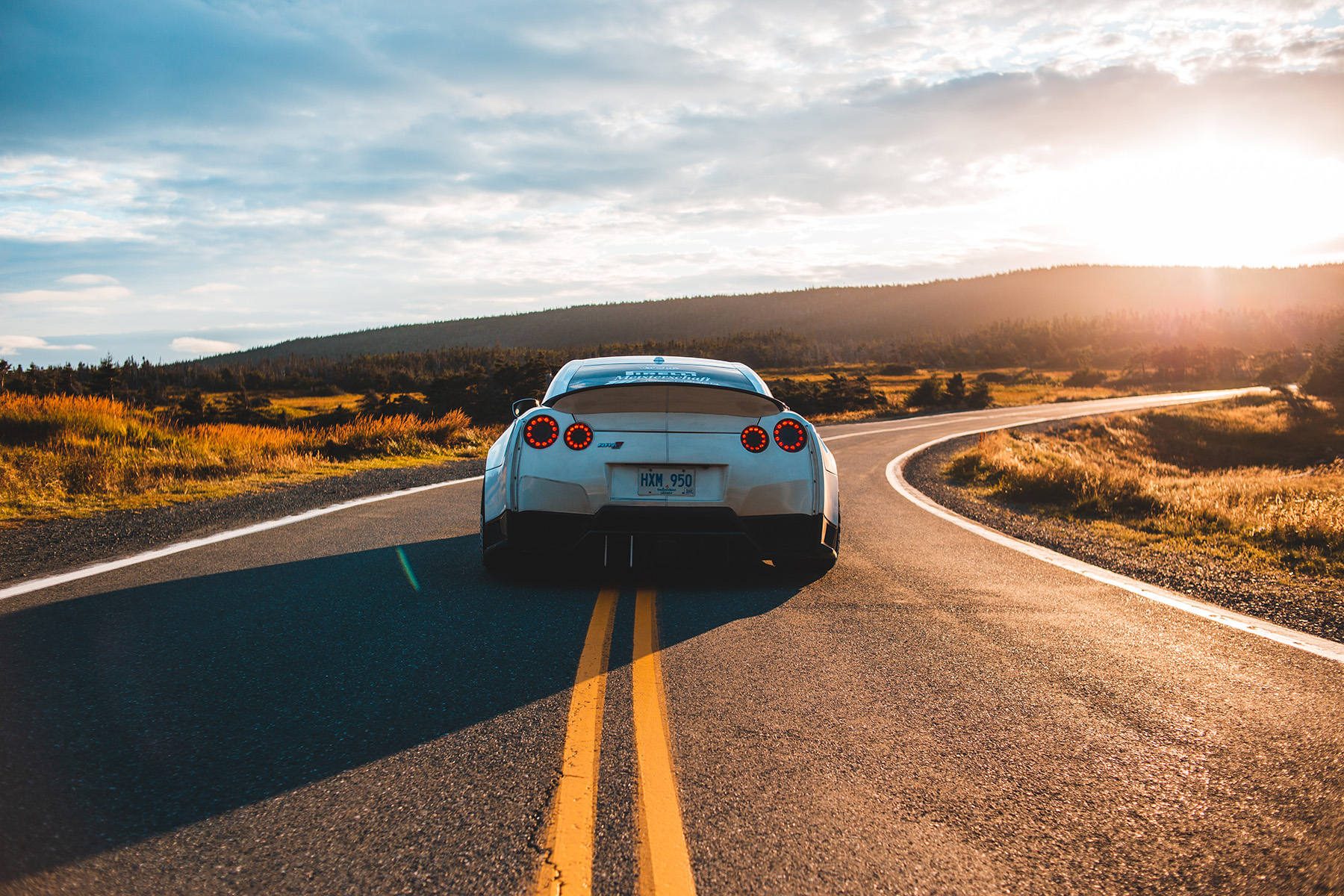 A car traveling down an open highway under a clear sky.