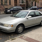 Parked Sedan on a Brooklyn Brownstone Block Silver sedan parked beside Brooklyn brownstones with stoops and autumn leaves along the curb.