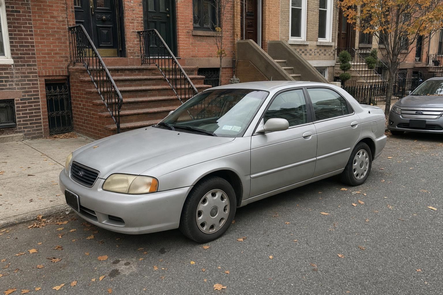 Silver sedan parked along a Brooklyn brownstone block with stoops and autumn leaves.
