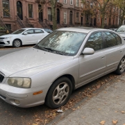 Parked Car on a Brooklyn Brownstone Block An older passenger car parked curbside beside Brooklyn brownstones with raised stoops.