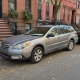 A parked car along a Brooklyn block of brick rowhouses and stoops