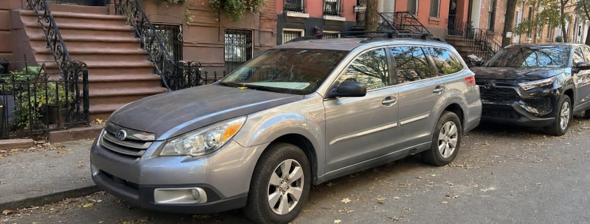 A parked car along a Brooklyn block of brick rowhouses and stoops