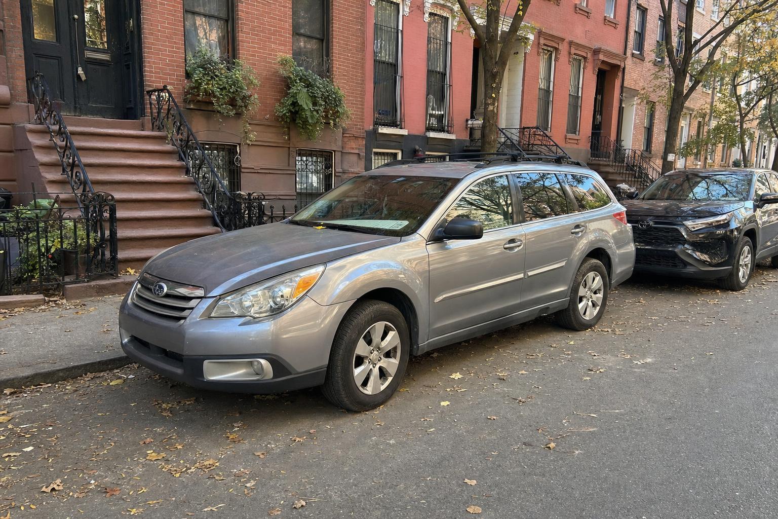 A parked car along a Brooklyn block of brick rowhouses and stoops