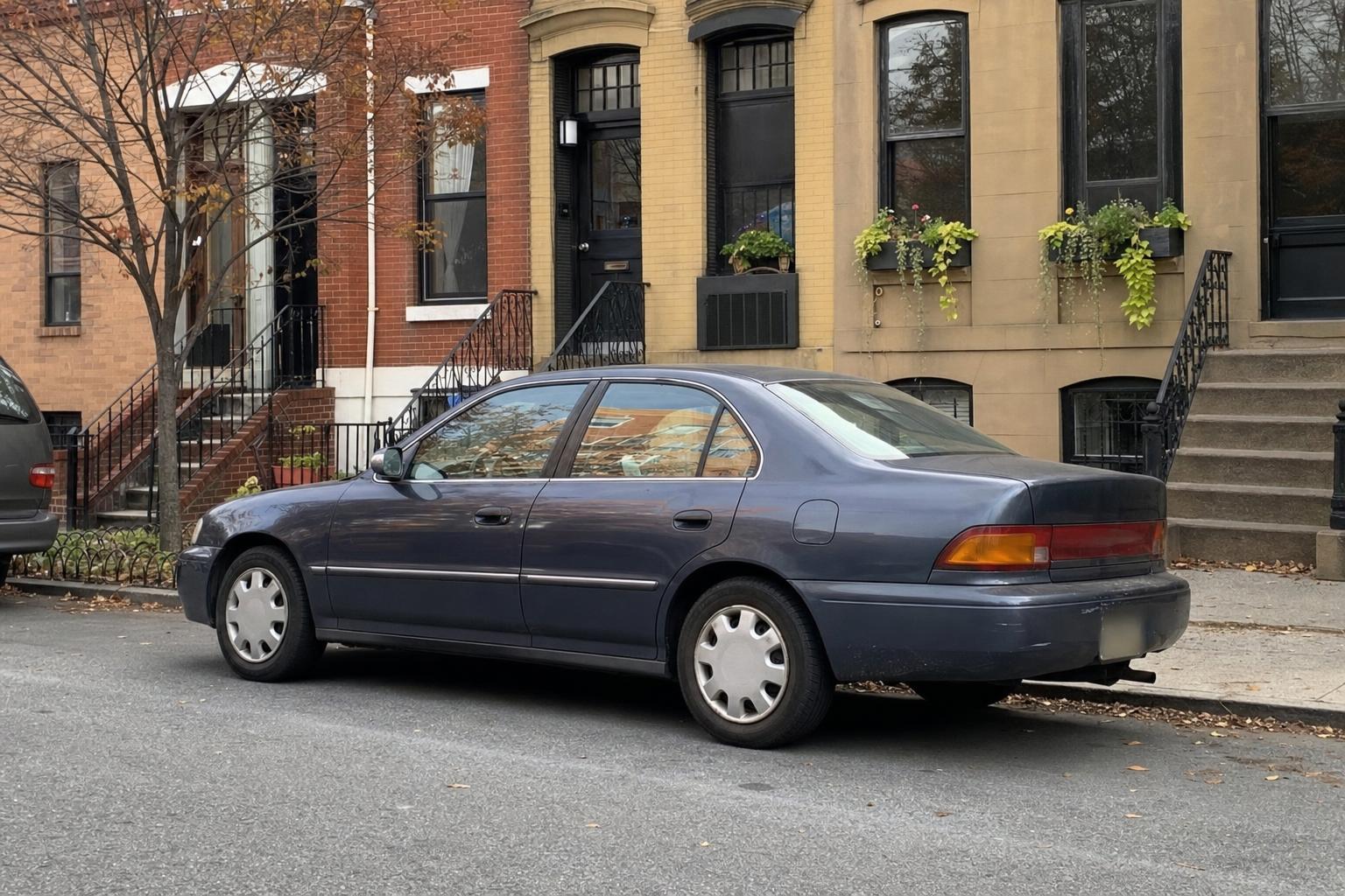 An ordinary used car parked along a Brooklyn brownstone block with stoops and curbside parking.