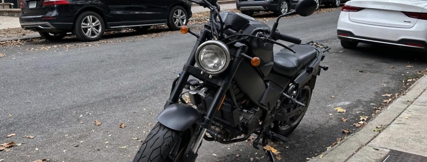 A motorcycle parked beside a brownstone stoop on a Brooklyn residential street.