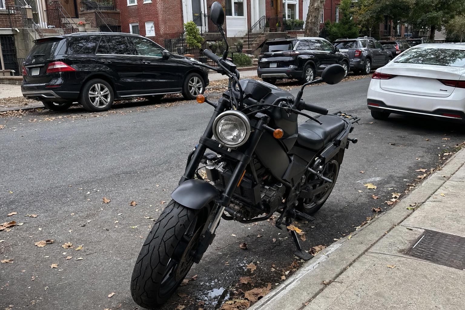 A motorcycle parked beside a brownstone stoop on a Brooklyn residential street.