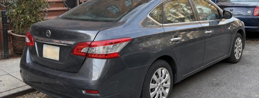 A parked car on a Brooklyn residential block with rowhouses, stoops, and curbside parking