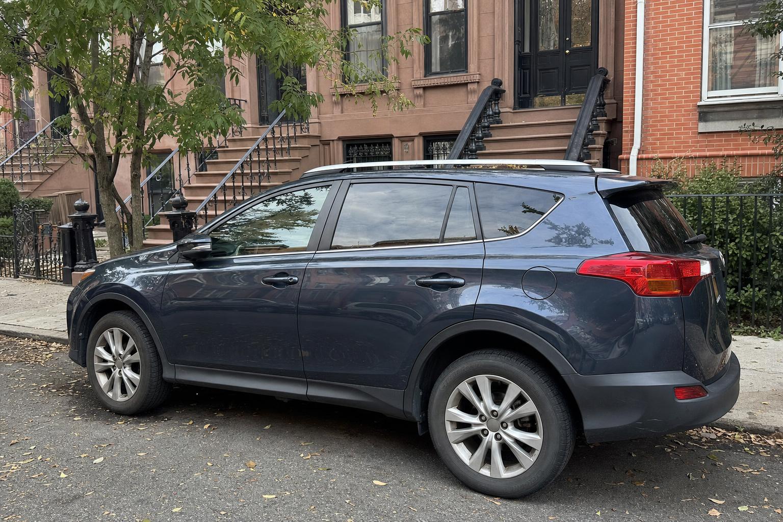 Unbranded vehicle parked beside brownstone stoops on a Brooklyn residential street