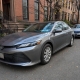A parked sedan on a Brooklyn residential street with brownstone buildings nearby