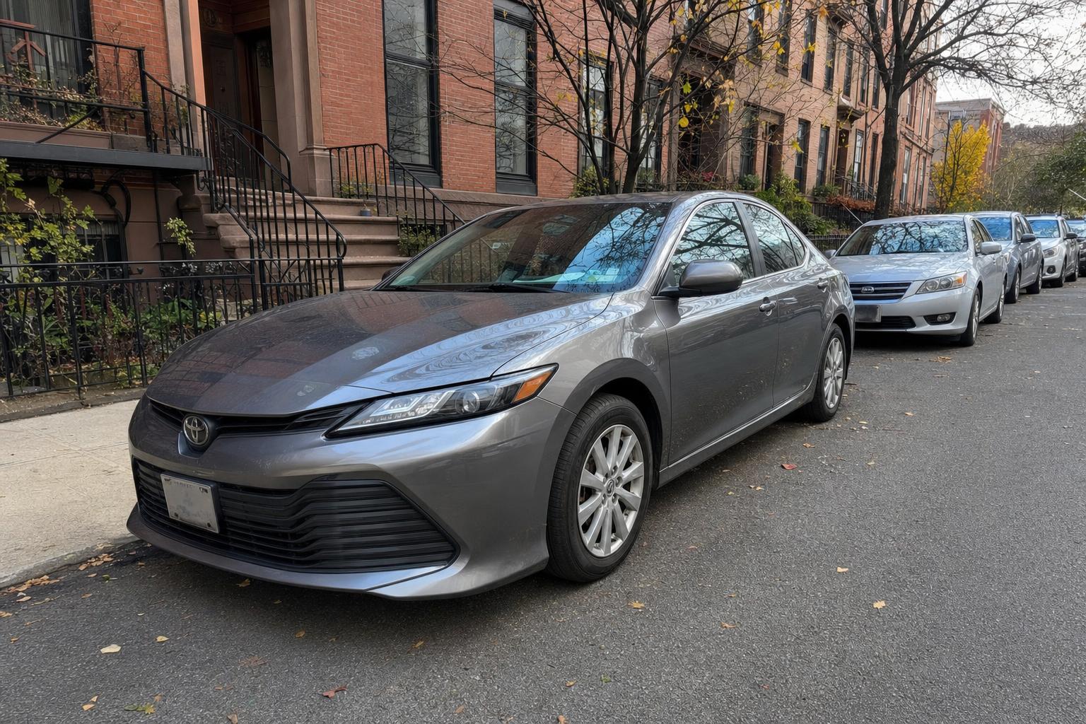 A parked sedan on a Brooklyn residential street with brownstone buildings nearby