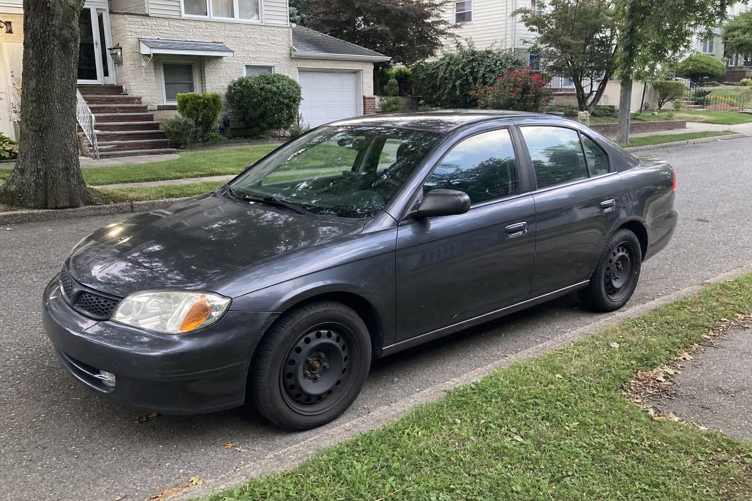 A used vehicle parked on a tree-lined residential street on Staten Island