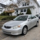 Silver sedan parked in a Staten Island driveway beside detached homes and mature trees.