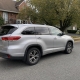 Silver SUV parked on a residential street in front of homes and mature trees on Staten Island