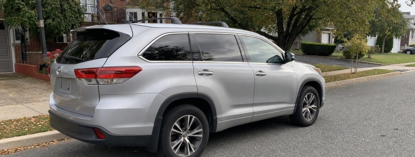 Silver SUV parked on a residential street in front of homes and mature trees on Staten Island