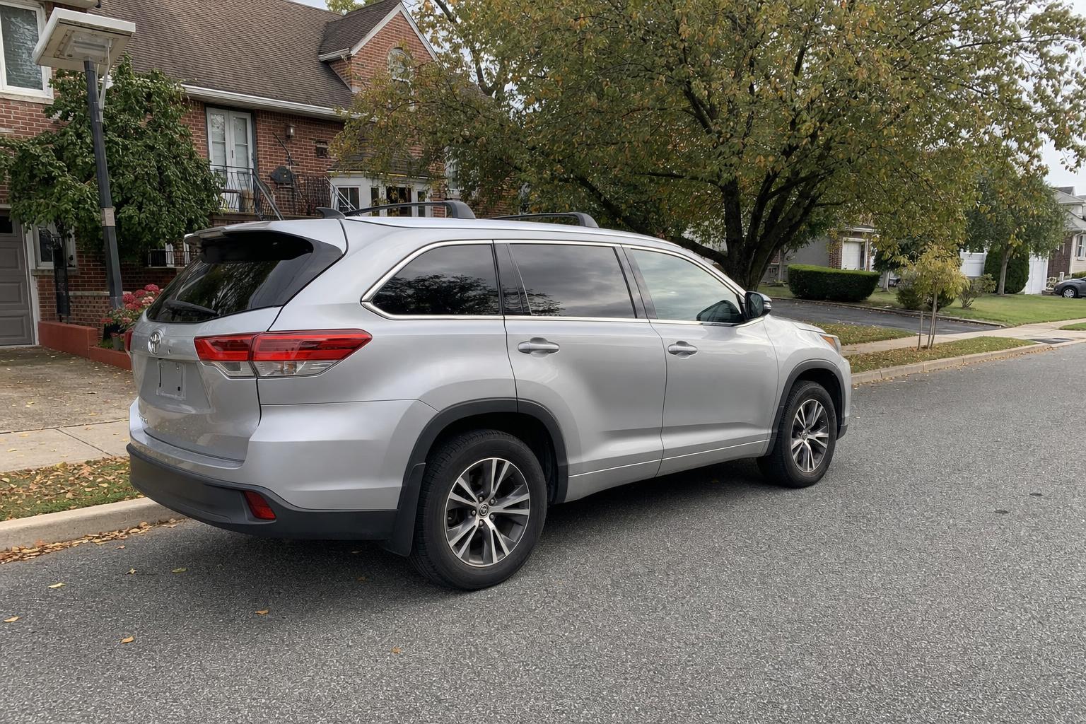 Silver SUV parked on a residential street in front of homes and mature trees on Staten Island