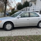 Silver sedan parked in a Staten Island driveway beside detached homes and autumn trees.