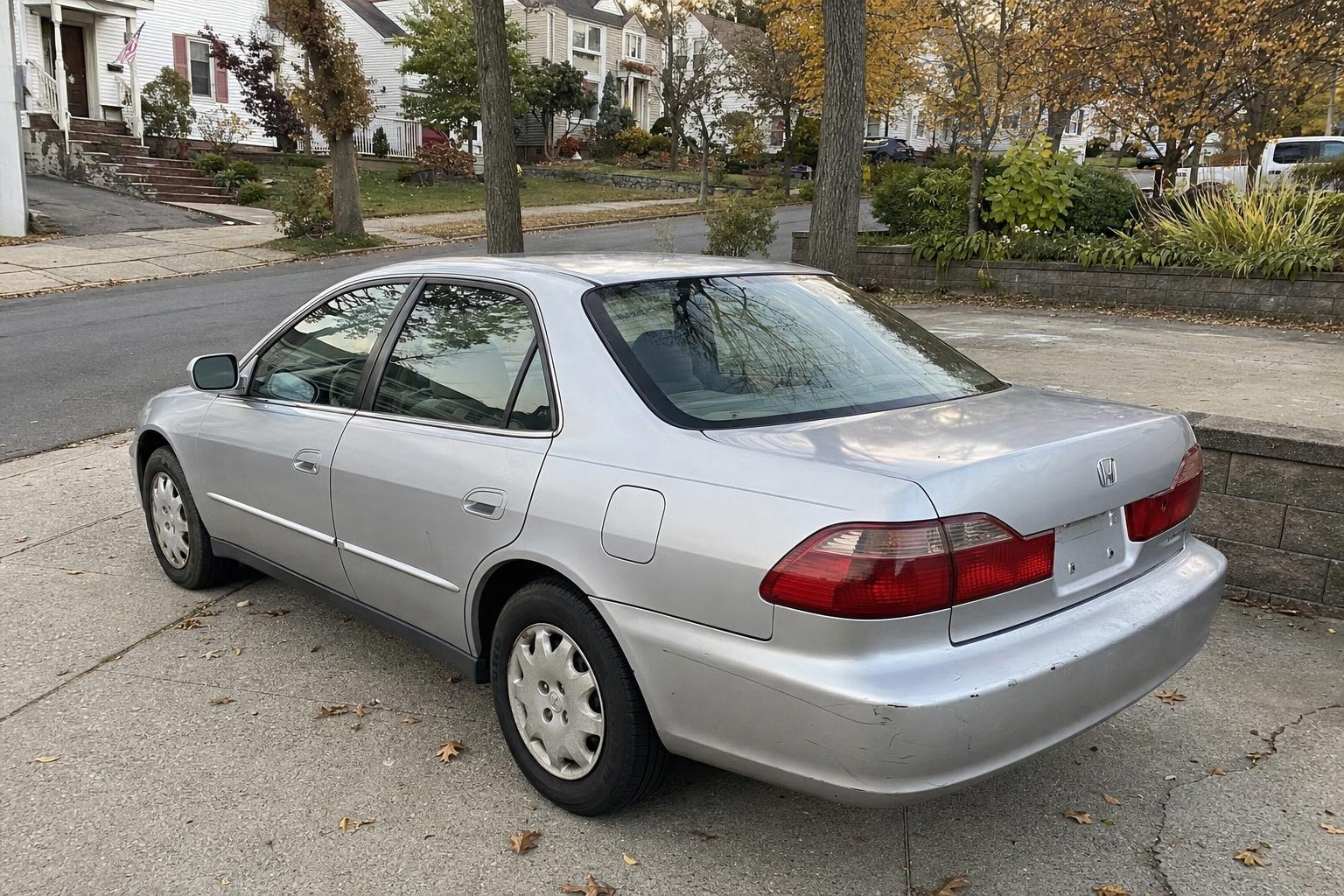 Silver sedan in a Staten Island driveway beside detached homes and autumn trees.