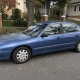 A blue sedan parked on a tree-lined Staten Island residential street