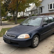 Parked Sedan in a Staten Island Driveway Older sedan parked in a Staten Island driveway beside detached homes and mature trees.