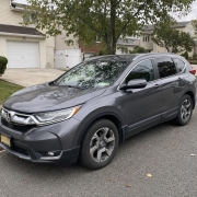 A Honda CR-V on a Staten Island Residential Street A gray Honda CR-V parked on a Staten Island residential street in front of detached homes and trees.
