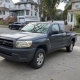 Used pickup truck parked in a Staten Island driveway beside detached homes and mature trees.