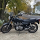 Older motorcycle parked in a Staten Island driveway near detached homes and mature trees.